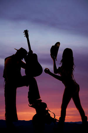 A silhouette of a couple in the sunset with a guitar.の写真素材
