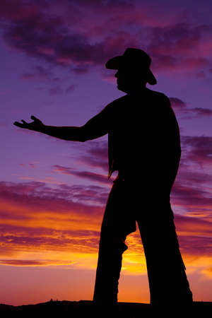 A silhouette of a cowboy with his arm reached out.の写真素材