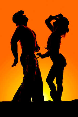 A silhouette of a cowgirl and her cowboy, looking up.の写真素材