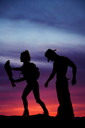 a silhouette of a woman hiker with a map, with a man standing close behind her.の写真素材