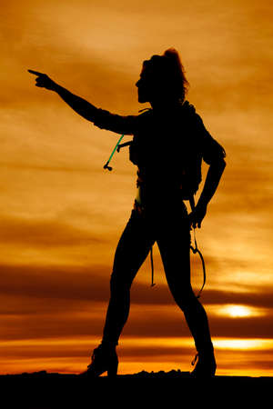 A silhouette of a woman hiker pointing in the direction to go.の写真素材