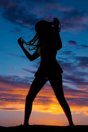 A woman silhouetted in the sunset standing.の写真素材
