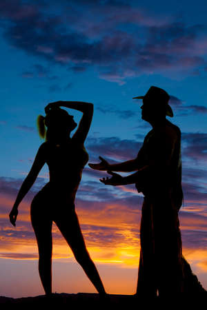 a silhouette of a cowboy reaching out for the one he loves.の写真素材