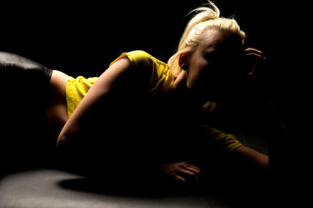 a woman in shadows looking away, her face is hidden in the sadowの写真素材