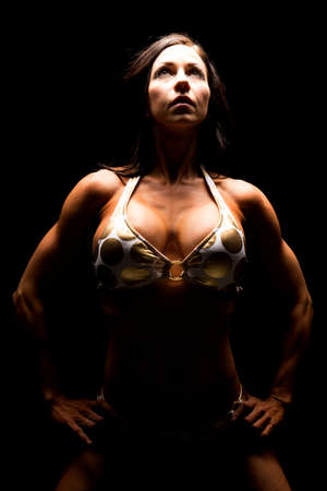 A woman in a gold bikini on her knees highlighted.の写真素材