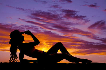 A silhouette of a beautiful cowgirl in the sunset.の写真素材