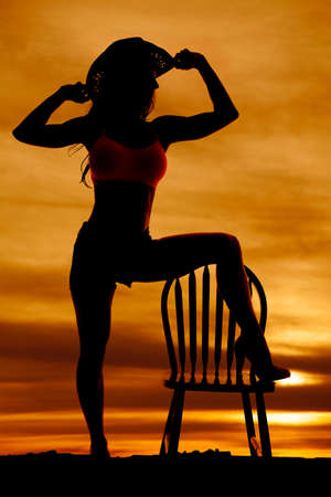 Silhouette of a sexy cowgirl woman with her foot on a chair.の写真素材