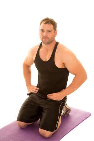 A man kneeling down on his fitness mat, with her hand on her hips.の写真素材