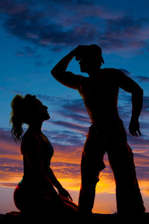 A silhouette of a woman kneeling in front of her cowboy.の写真素材