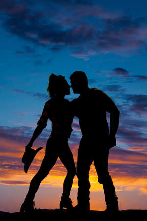 a silhouette of a cowgirl and cowboy in each others arms.の写真素材
