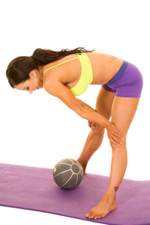 A woman bending over after a hard workout with a weighted medicine ball, with a tattoo on her ankle.の写真素材