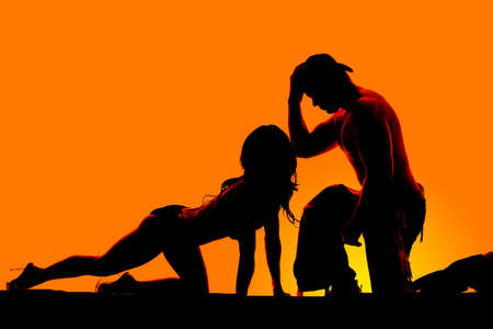 a silhoutte of a woman crawling on her hands and knees towards her cowboy.の写真素材