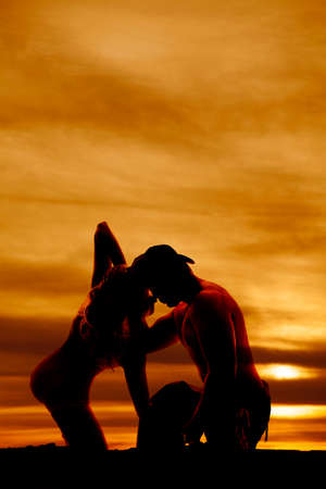 A silhouette of a cowboy wrapped up with his woman.の写真素材