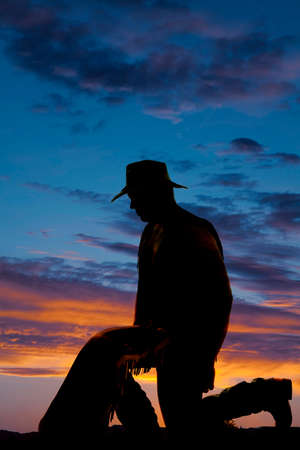 a silhouette of a cowboy on his knees praying.の写真素材