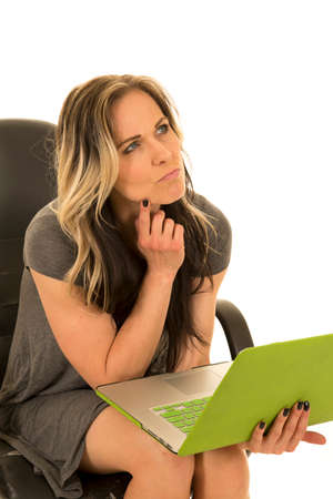 A woman sitting in her office chair, deep in thought about something on her laptop.の写真素材