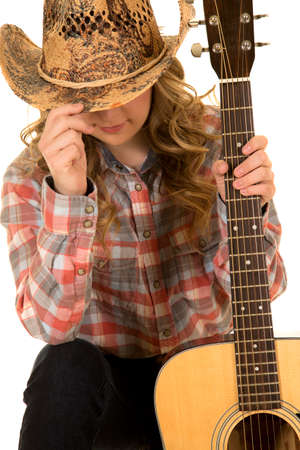 a cowgirl hiding her face, holding onto her guitar.の写真素材