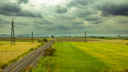 A horizontal shot of railroad tracks extending to the horizon on a cloudy dayの写真素材