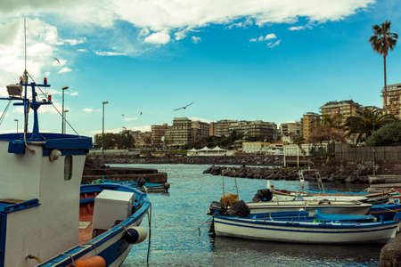 Several small colorful boats are anchored in the harbor of Catania, SIcily-Italy on the coast of the Mediterranean Sea.のeditorial素材