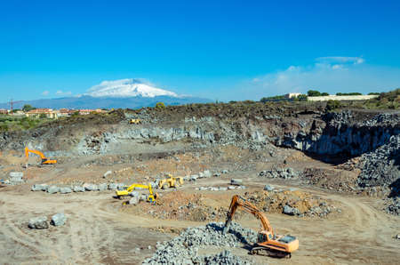 the excavator in a sicilian mine in a day's work. On background the volcano Etnaの写真素材