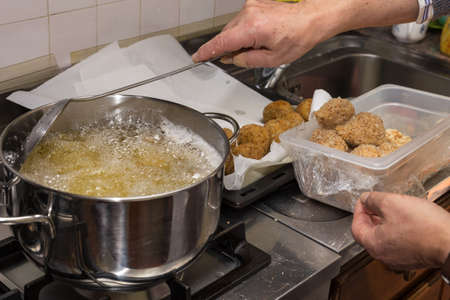 Chef frying food in flaming pan on gas hob in commercial kitchen.の写真素材