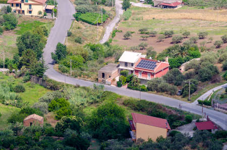 the winding country road, with some houses and solar systemsの写真素材