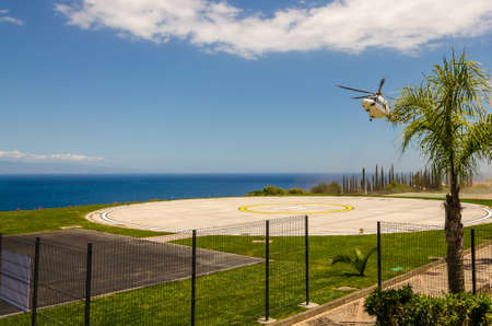 Helicopter landing on a heliport with the blue sea in the backgroundの写真素材