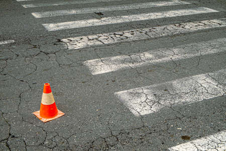 Two-colored traffic cone placed in a rough city street