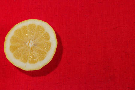 Detail of fresh sliced lemon on a rustic canvas fabric texture in red woven colorの写真素材