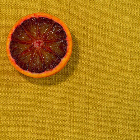 Detail of fresh sliced tarot orange on a rustic canvas fabric texture in yellow woven colorの写真素材