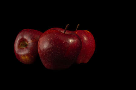 Three juicy red apples on a black background.の写真素材
