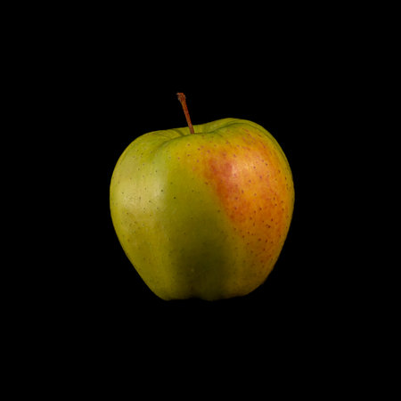 a yellow apple on a black background, ideal for wallpapersの写真素材