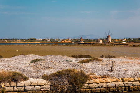 The coastal landscape of west Sicily is dotted with traditional salt pans and windmills, capturing the essence of the island's rich history and natural resources.の写真素材