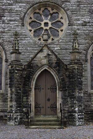 An old church doorway  with a stained glass circular windowの写真素材