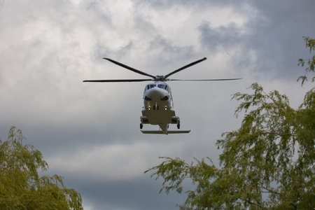 A view looking up at a close up of a helicopter just above the tree line as it approaches to land....