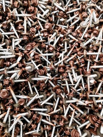 A lot of silver metal tack nails together, with blue grey light