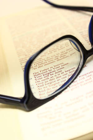 Bible open to the lord's prayer with a pair of glasses on the pages.