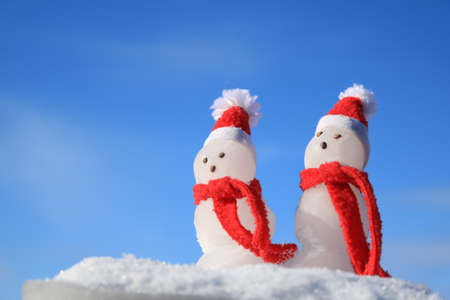 Snowmen isolated against a blue sky.の写真素材