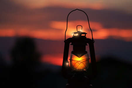 Burning lantern illuminated by and orange sunsetの写真素材
