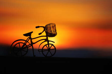 Toy bicycle silhouetted by a beautiful sunsetの写真素材