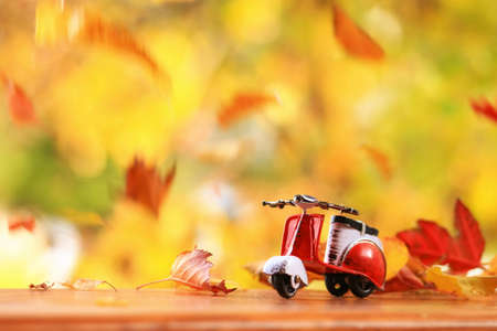 Autumn scence of a scooter surounded by falling leavesの写真素材