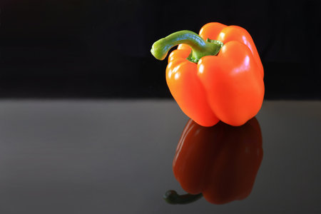 Orange bell pepper on a reflective black background.の写真素材
