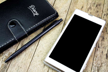 smart phone, pen and notebook on wood table