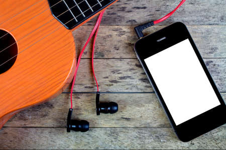 Guitar, earphones and smart phone on a wood table
