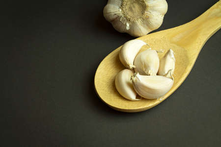 group of garlic on a ladle on black backgroundの写真素材