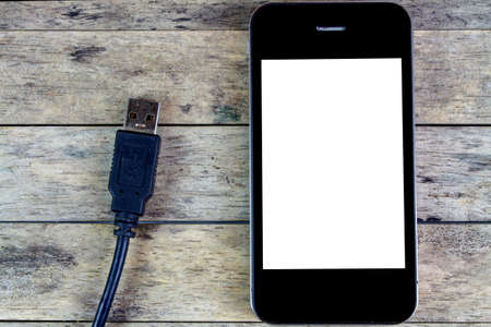 smart phone and usb cable on a wooden table