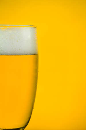 beer in a glass on yellow backlight background, soft focused, close-upの写真素材