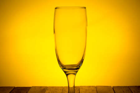 empty wineglass on yellow backlight background, closed upの写真素材