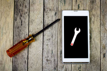 smart phone and screwdriver for repair on wood plank, top viewの写真素材