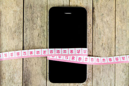 smart phone and measure tape on wood backgroundの写真素材