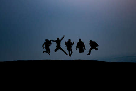 group of young people is jumping on top of the mountainの写真素材